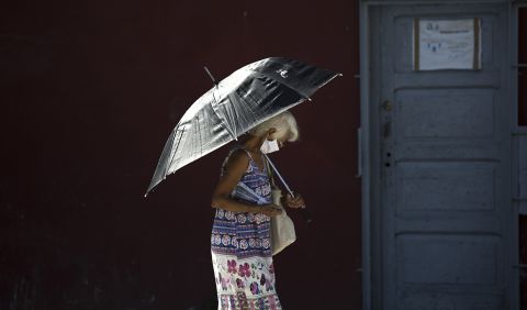 A pedestrian wearing a face mask amid the coronavirus pandemic uses a parasol in Havana, Cuba, on Monday, August 10. 