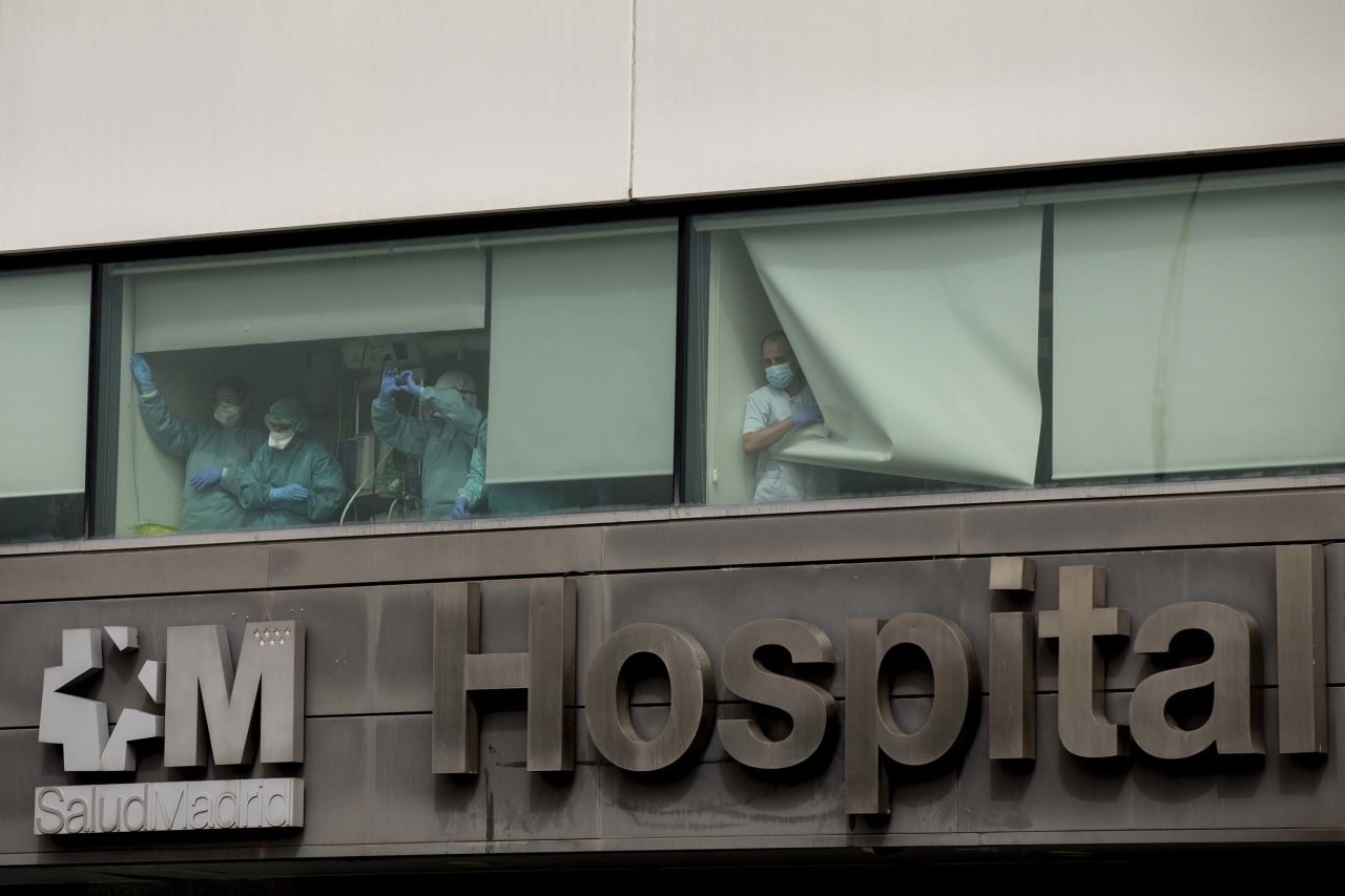 Medical staff wave from a window at La Paz Hospital in Madrid, Spain, on March 18, as the country works to stop the spread of the coronavirus.