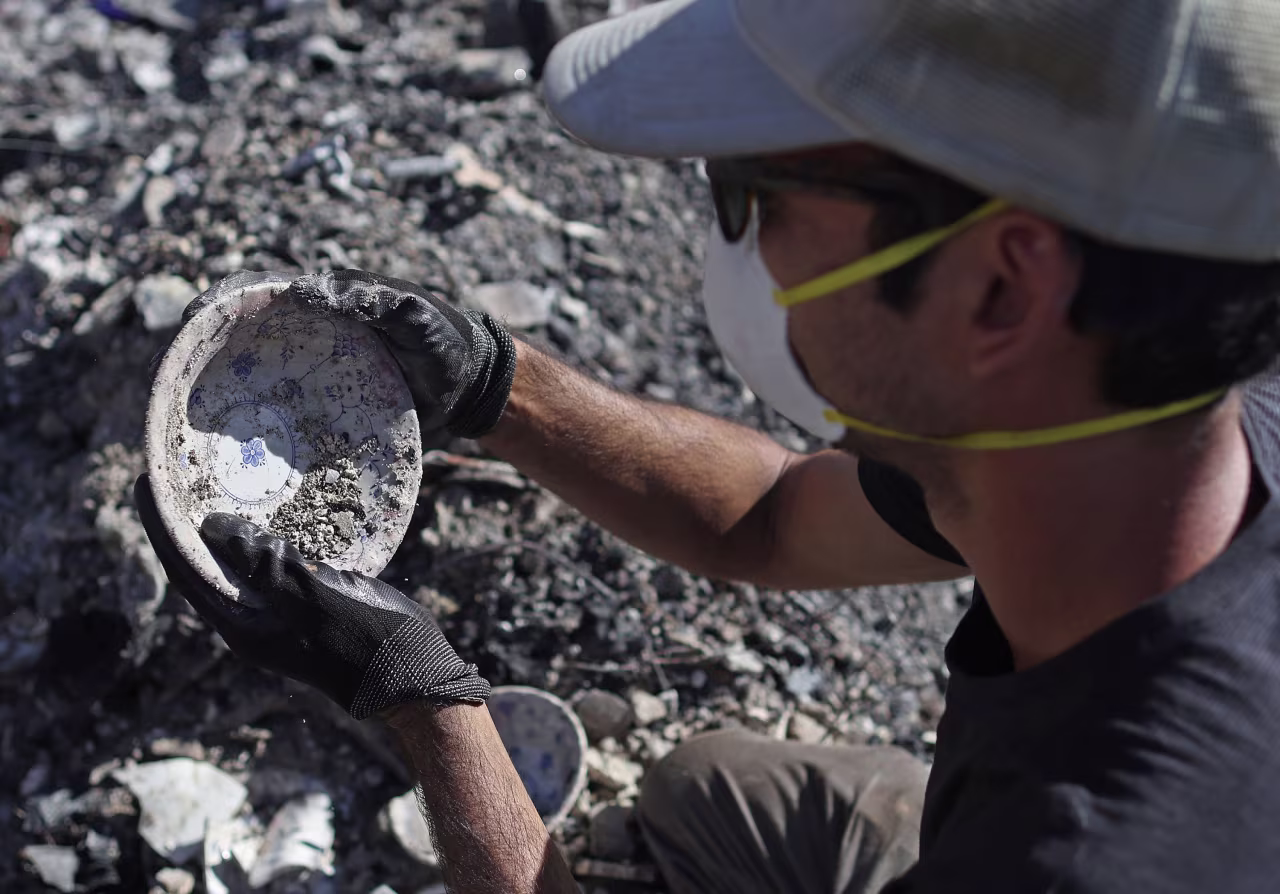 Brook Cretton salvages a bowl he found while sifting through the rubble of a home destroyed by wildfire in Kula, Hawaii, on Saturday. 