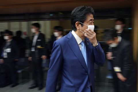 Japanese Prime Minister Shinzo Abe adjusts his face mask as he leaves a press conference in Tokyo on May 4.