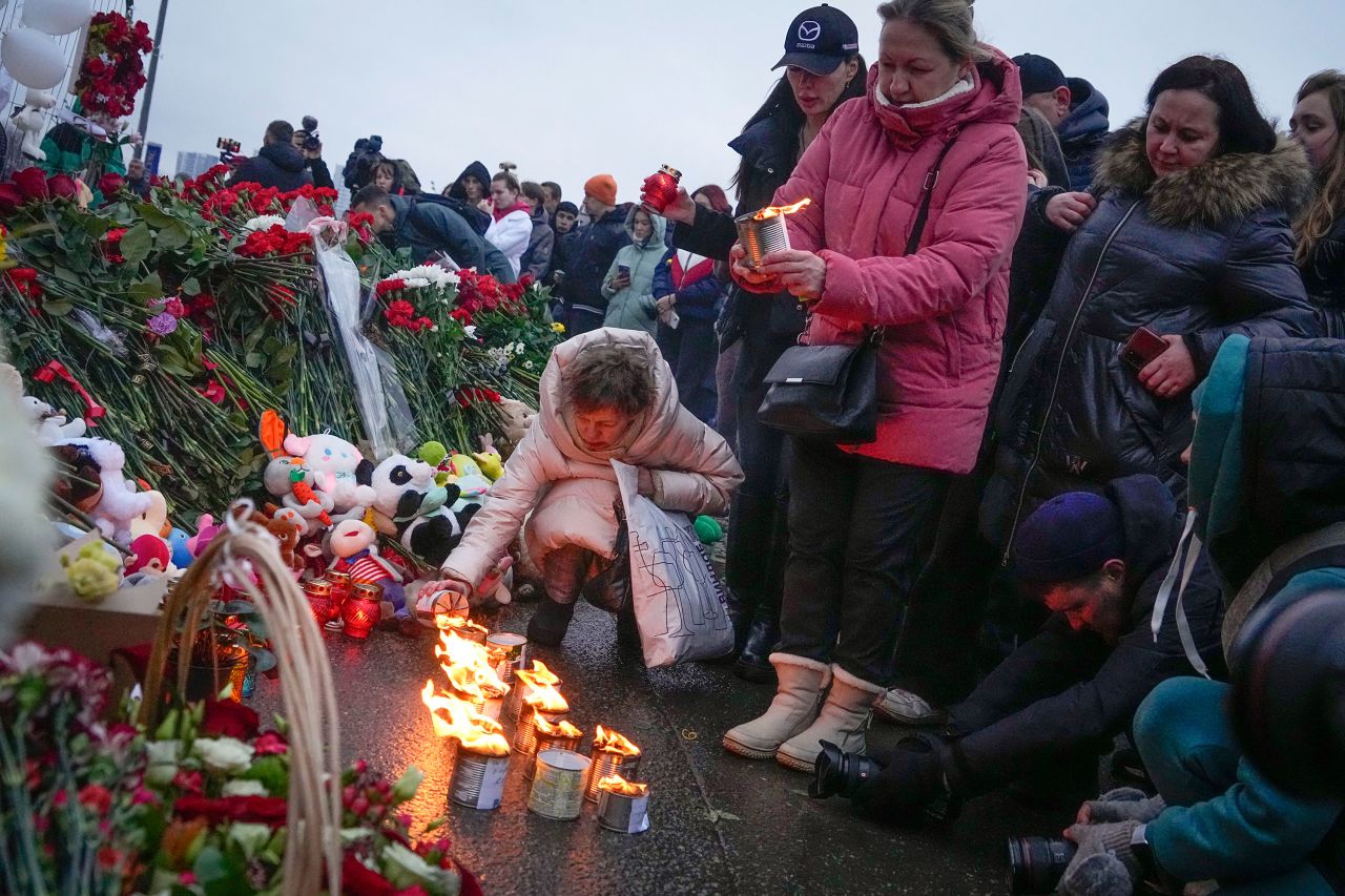 A woman lights candles at a memorial near Crocus City Hall, on the western edge of Moscow, on Saturday. 