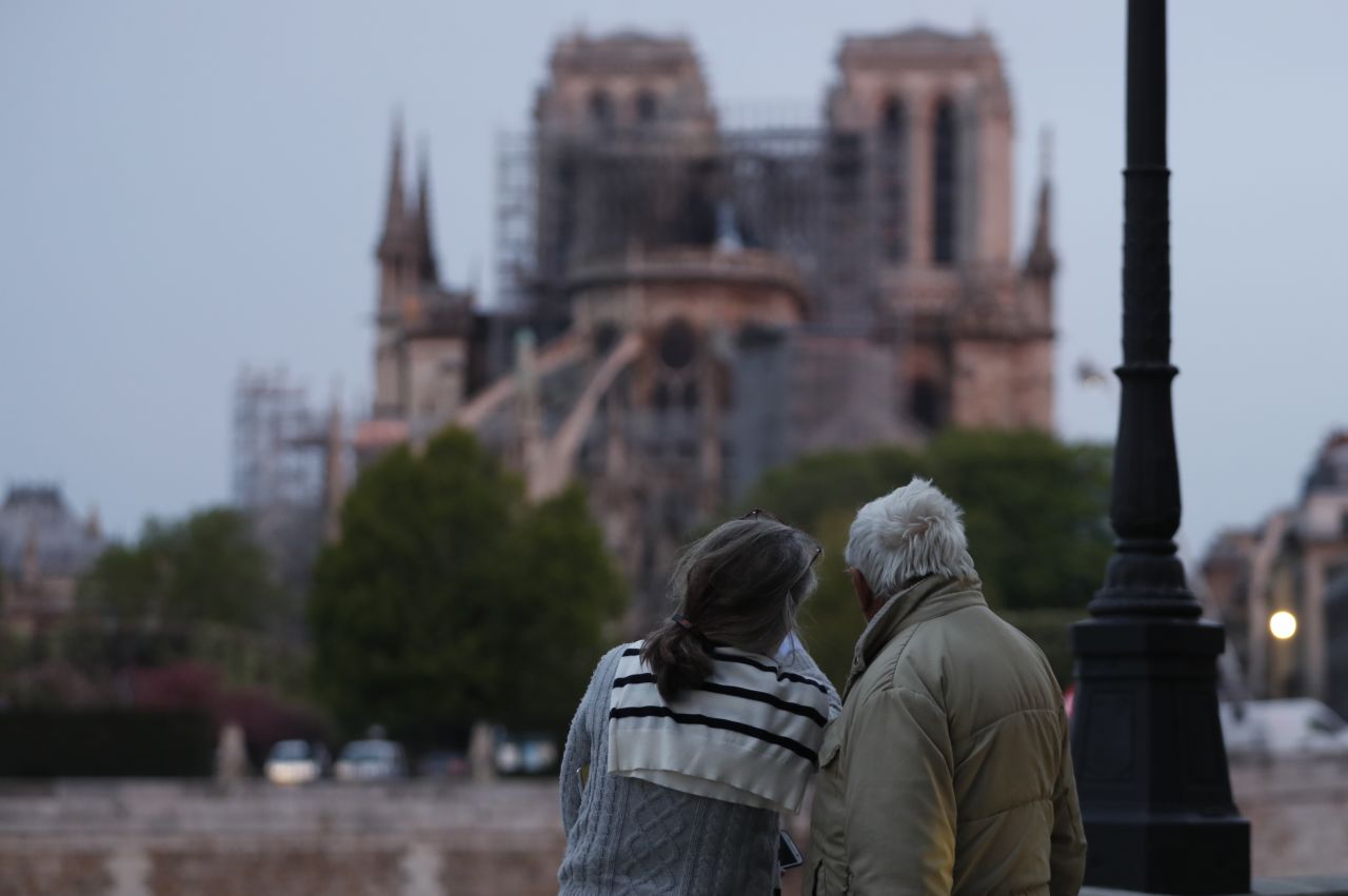 A couple looks on as firefighters work to extinguish a fire at Notre-Dame Cathedral in Paris early on Tuesday.