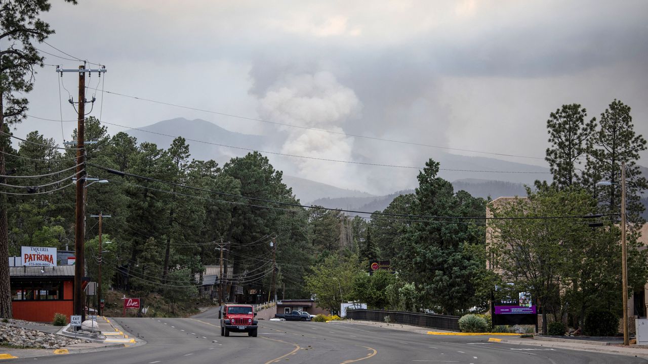 A plume of smoke rises from the South Fork fire as a vehicle passes through the evacuated town of Ruidoso, New Mexico, on June 19.