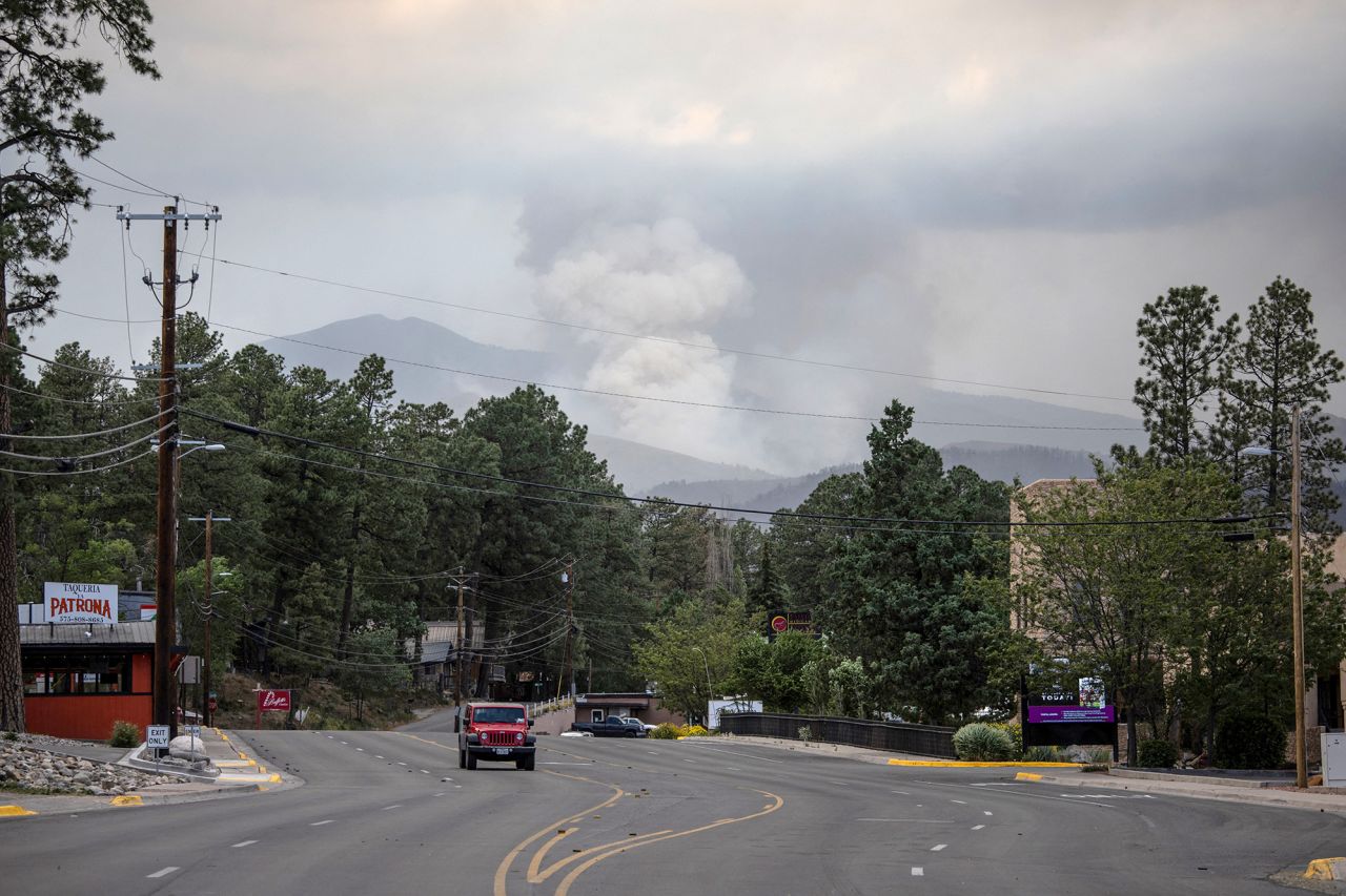 A plume of smoke rises from the South Fork fire as a vehicle passes through the evacuated town of Ruidoso, New Mexico, on June 19.