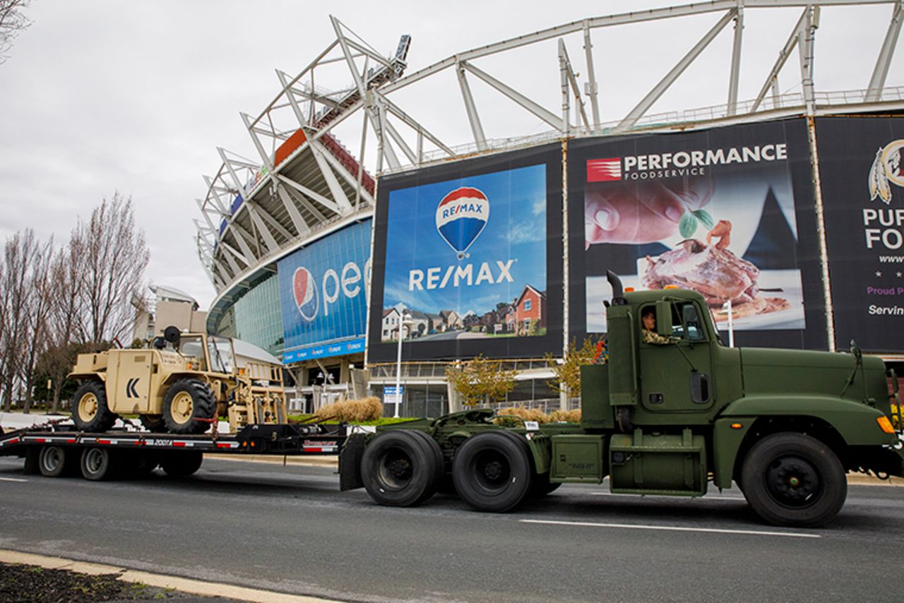 Equipment is driven by FedEx Field as the National Guard sets up tents to be used for coronavirus testing, Saturday, March 21, in a parking lot at the NFL football stadium in Landover, Maryland.