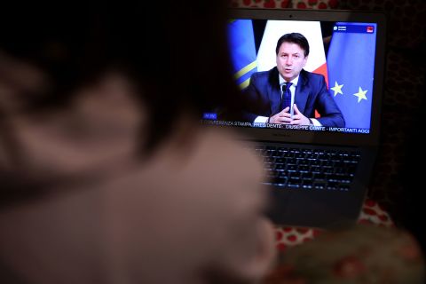 A girl watches Italian Prime Minister Giuseppe Conte announce the shut down of all non-essential production activities on March 21, in Rome, Italy.