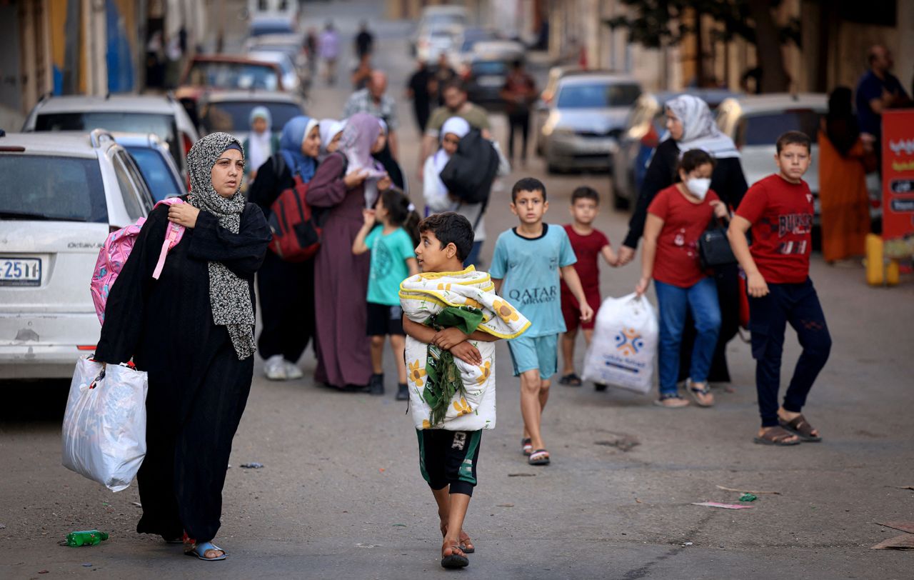 Palestinians carrying their belongings flee to safer areas in Gaza City after Israeli air strikes, on October 13, 2023.