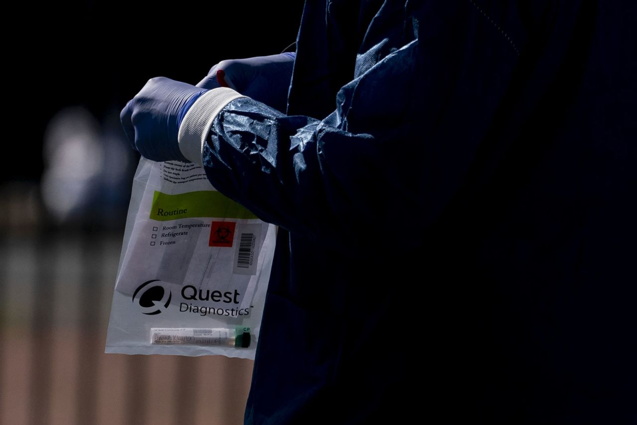 A healthcare worker holds a Quest Diagnostics bag containing a coronavirus swab at a drive-through testing center in Washington, DC.