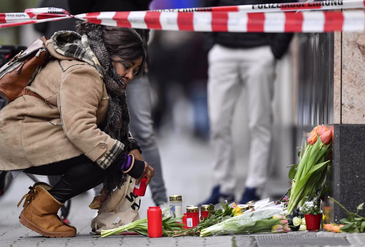 A woman places a candle at a makeshift victims' memorial near the scene of one of the shootings in Hanau.
