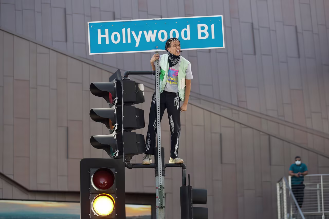 A demonstrator shouts slogans after climbing on a traffic light on June 7, in the Hollywood area of Los Angeles.