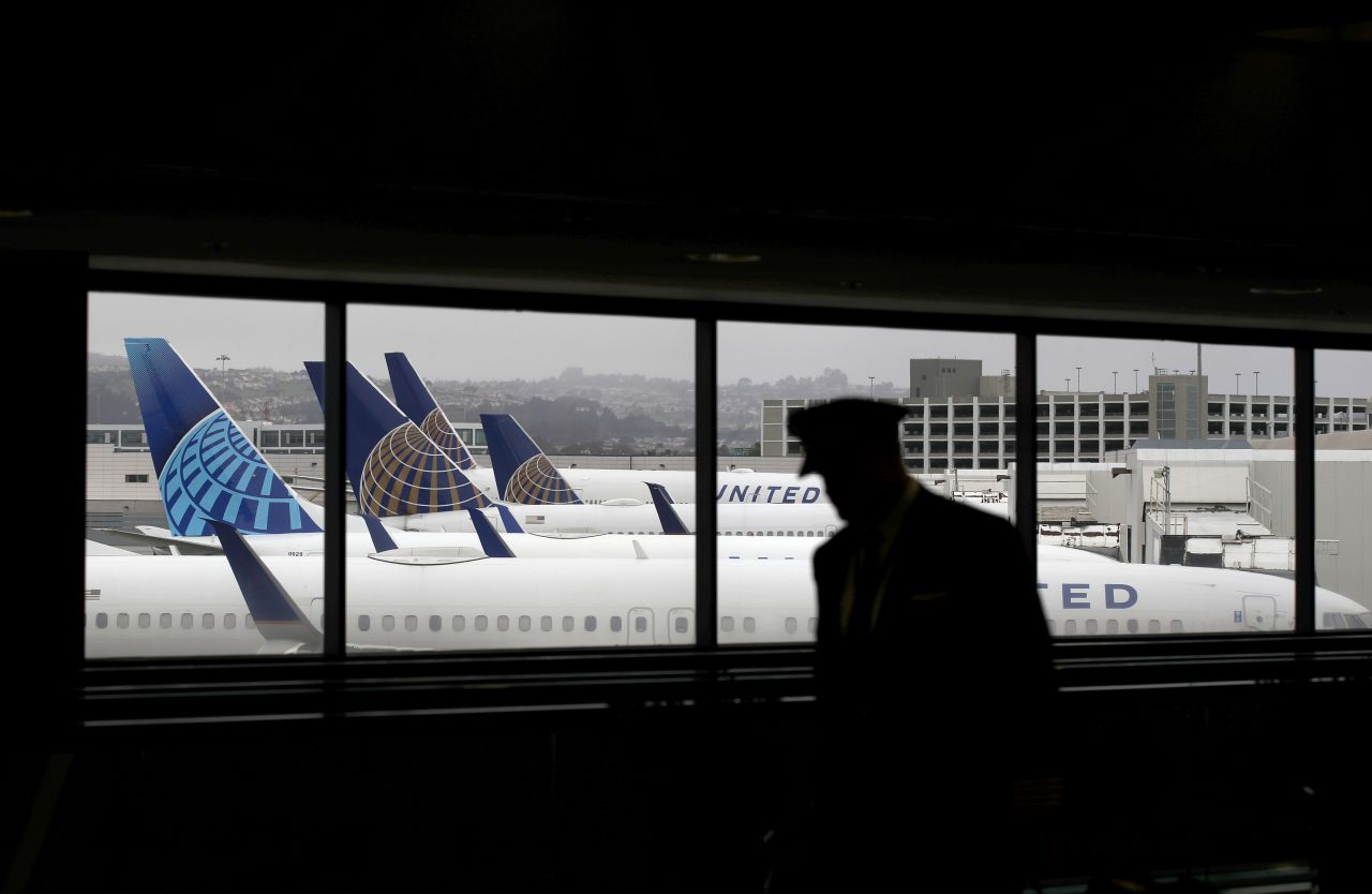 A pilot walks by United Airlines planes as they sit parked at gates at San Francisco International Airport on April 12.