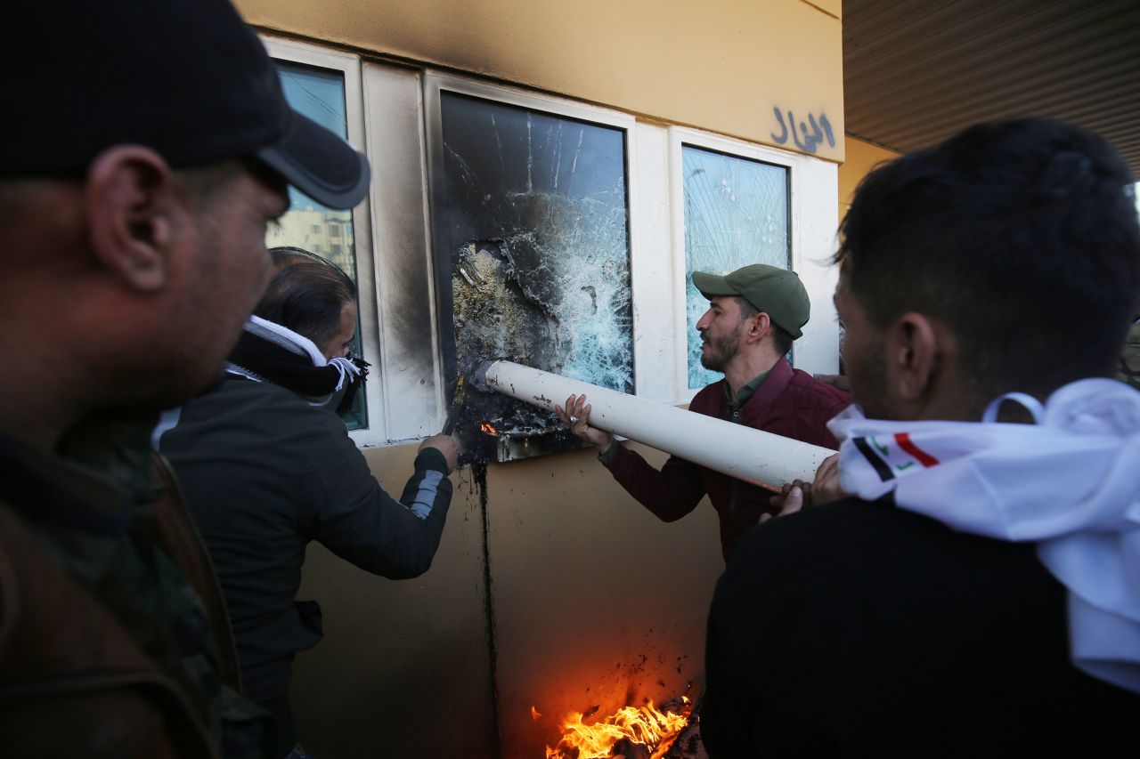 Protesters use a pipe to break the bullet-proof glass windows at the US embassy in Baghdad. Photo: Ahmad Al-Rubaye/AFP via Getty Images