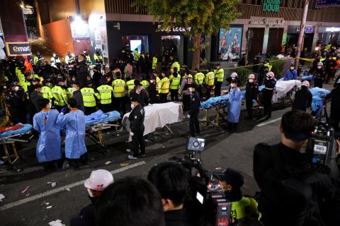 Rescue team members wait with stretchers to remove bodies from the scene on Saturday night in the Itaewon district, Seoul.