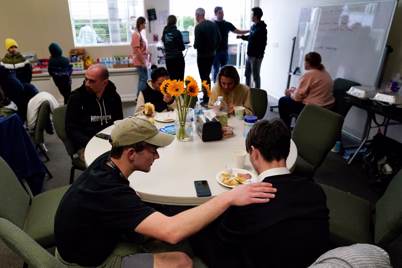 Volunteer Silas Breen, below left, from the Calvary Bible Institute, prays with David, from Ukraine, at Calvary San Diego's shelter for Ukrainians arriving from Tijuana, Mexico, last Friday, in Chula Vista, California.