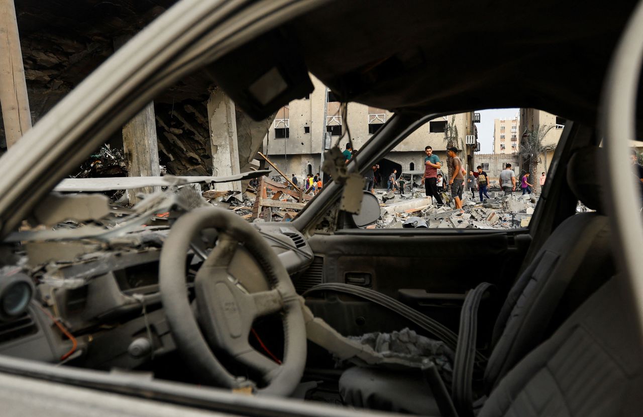 People inspect the site of Israeli strikes on a house in Khan Younis, Gaza, on Monday, October 23. 