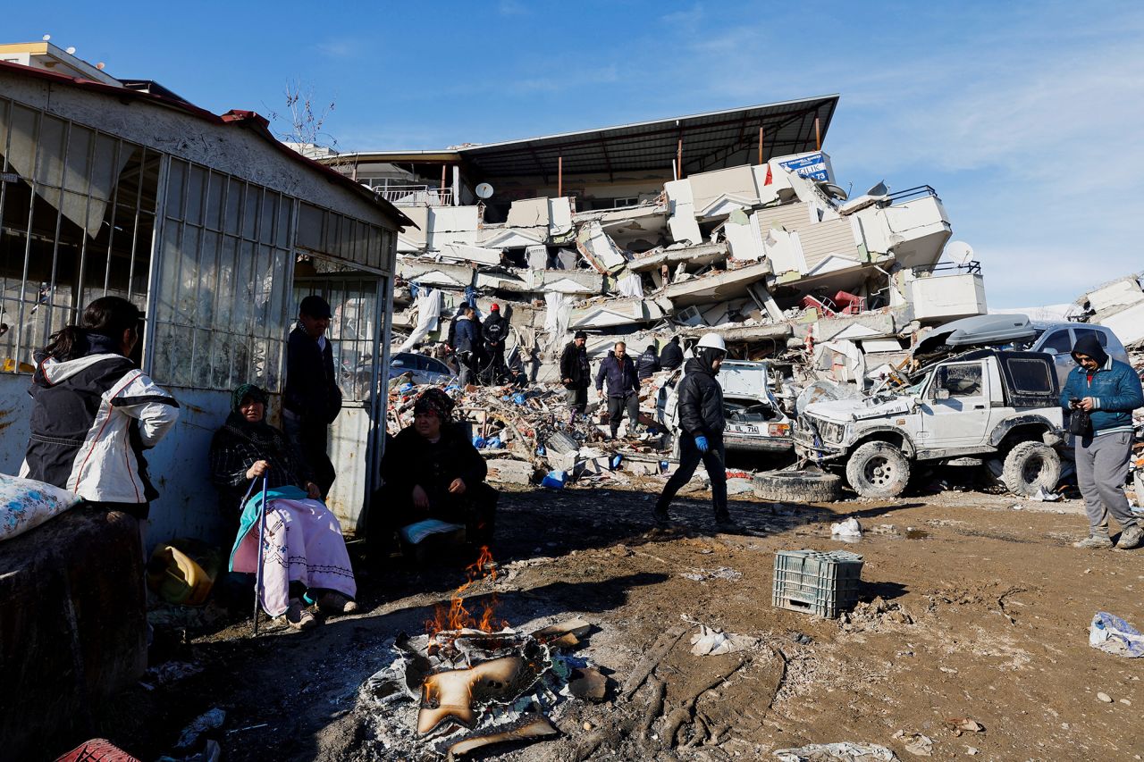 People sit next to a fire near the site of a collapsed building in?Kahramanmaras, Turkey, on February 7.