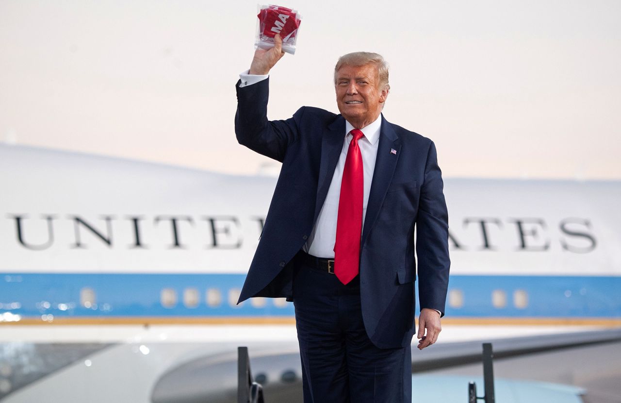 President Donald Trump holds masks before throwing them to supporters as he arrives to hold a Make America Great Again rally as he campaigns at Orlando Sanford International Airport in Sanford, Florida, October 12.