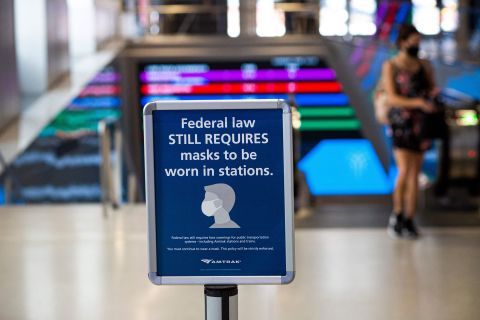 A woman walks past a sign calling for mask wearing at Penn Station in New York City, on August 2.