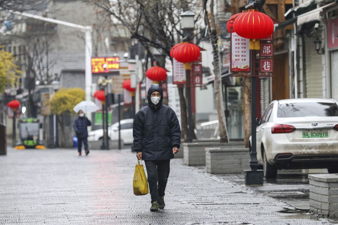 A man wearing a face mask walks through a Wuhan neighborhood Saturday.