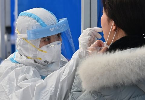 A medical staff member wearing protective gear takes samples for the Covid-19 test from a visitor at a testing station in Seoul, South Korea, on November 27.