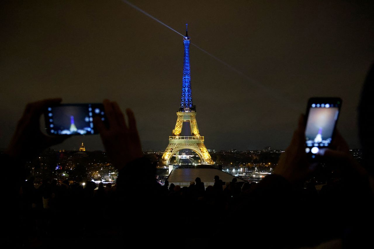 Members of the public capture images of the Eiffel Tower lit in the colours of the Ukrainnian flag in a show of support to Ukraine in Paris, France, on February 23.