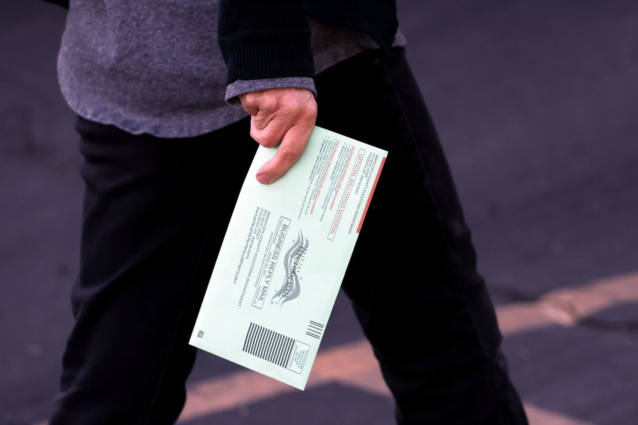 A voter holds their ballot as they arrive at the Burton Barr Library voting location on in Phoenix, Arizona, Tuesday. 