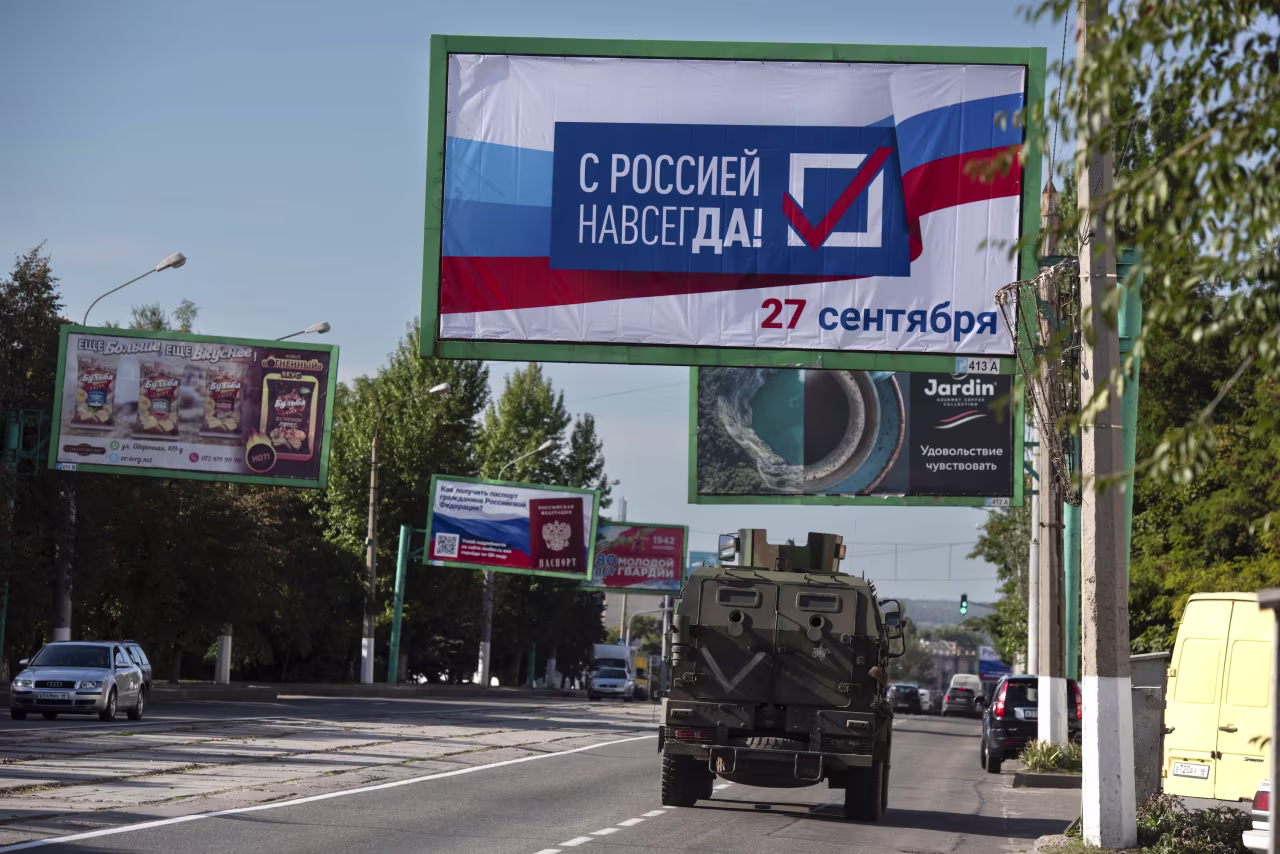A military vehicle drives along a street with a billboard that reads: "With Russia forever, September 27" prior to a referendum in Luhansk, controlled by Russia-backed separatists on September 22, 2022.
