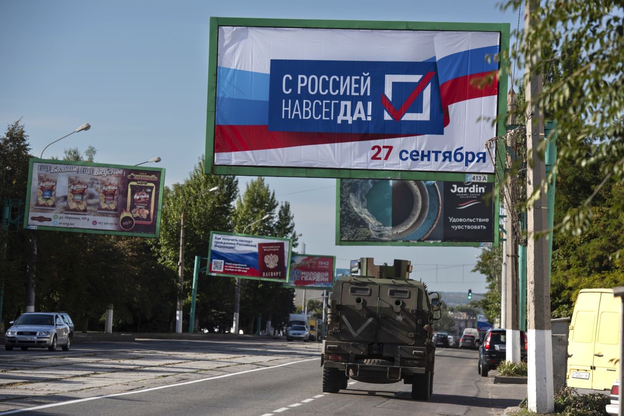 A military vehicle drives along a street with a billboard that reads: "With Russia forever, September 27" prior to a referendum in Luhansk, controlled by Russia-backed separatists on September 22, 2022.