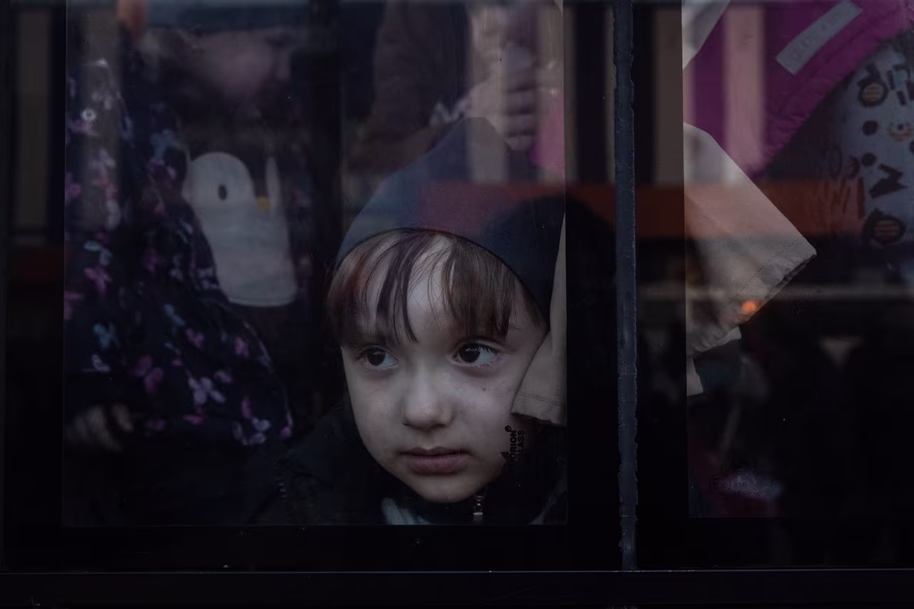 A child looks out the window of a bus after a large convoy of cars and buses arrived at an evacuation point, carrying hundreds of people evacuated from Mariupol and Melitopol on March 25, in Zaporizhzhia, Ukraine. 