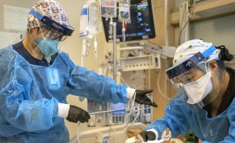Registered nurse Akiko Gordon, left, and Repertory Therapist Janssen Redondo, right, are working inside the ICU with a covid-19 positive patient at Martin Luther King Jr. Community Hospital (MLKCH) on Friday, December 31, 2021 in Los Angeles, CA. 