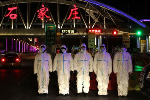 Police officers wearing protective suits stand guard at the entrance of an expressway on January 6 in Shijiazhuang, Hebei Province, China.