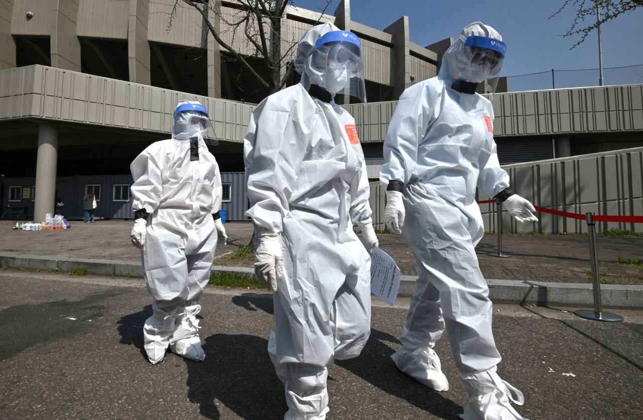 City officials wearing protective clothing arrive at a coronavirus testing station set up at Jamsil Sports Complex in Seoul on April 3.