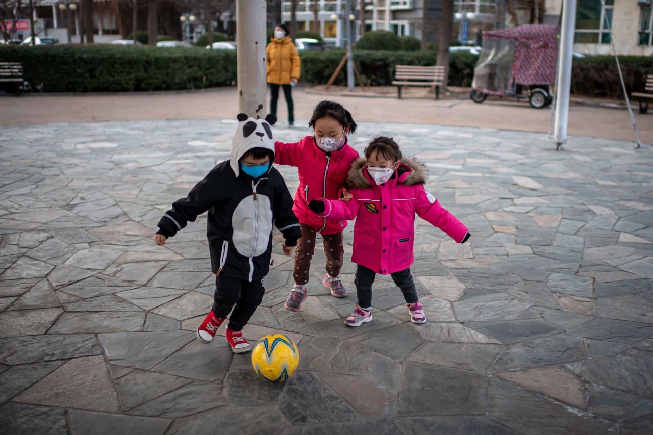 Children wearing protective facemasks to help stop the spread of the Wuhan coronavirus play soccer inside a condominium complex in Beijing.