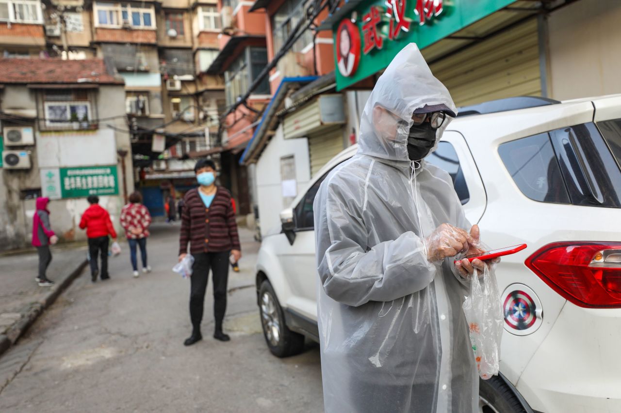 A resident dressed in a protective suit lines up with others to pick up pork which was delivered to their quarantined compound in Wuhan, in China's central Hubei province on March 18.