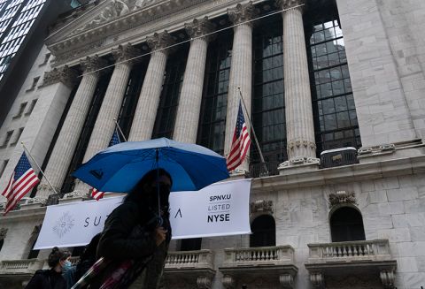 A woman with an umbrella passes the New York Stock Exchange, Monday, Oct. 26, 2020. 
