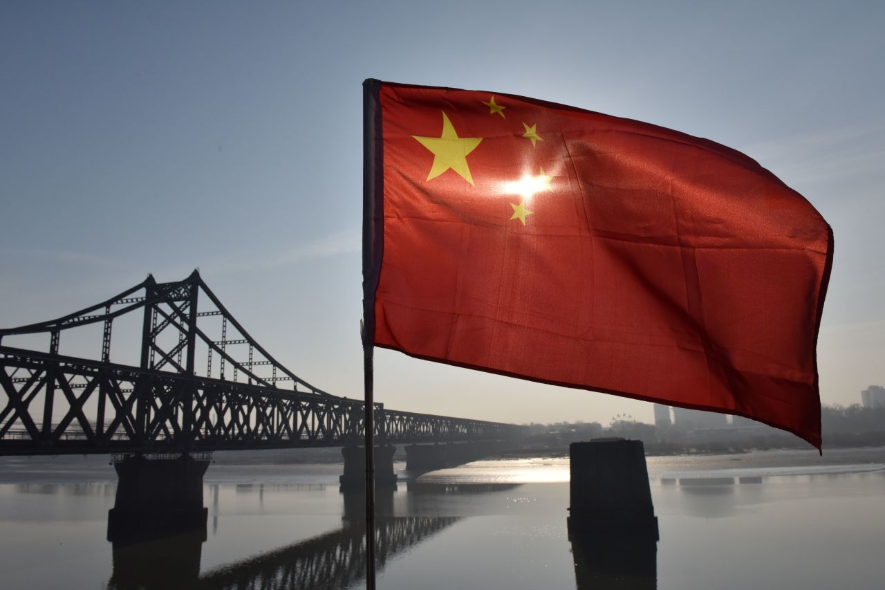 The Chinese flag flies on the Yalu River Broken Bridge, with the Sino-Korean Friendship Bridge, and the North Korean city of Sinuiju behind it, in the Chinese city of Dandong on February 23, 2019.