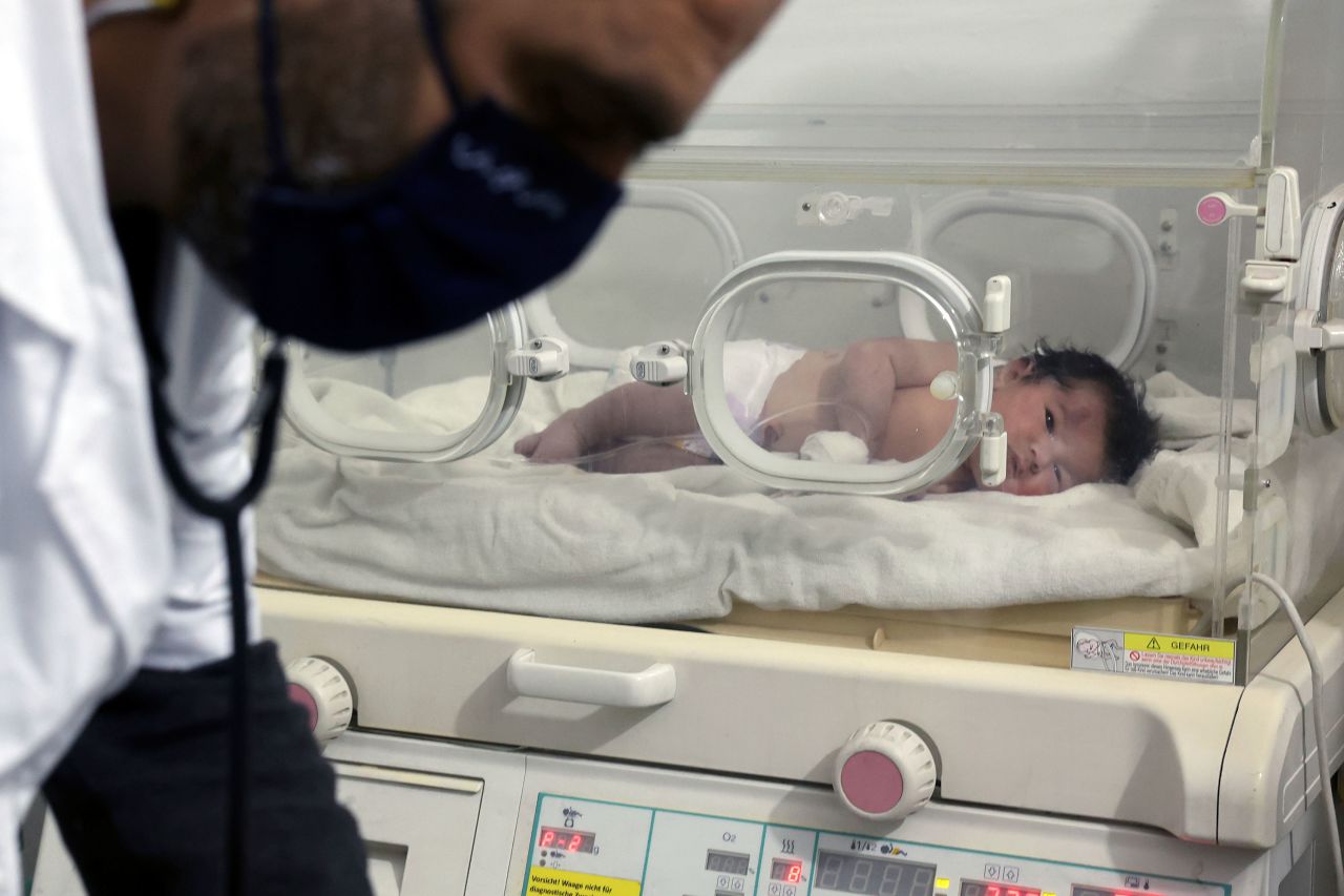 A doctor works while the baby lies in an incubator at the hospital.