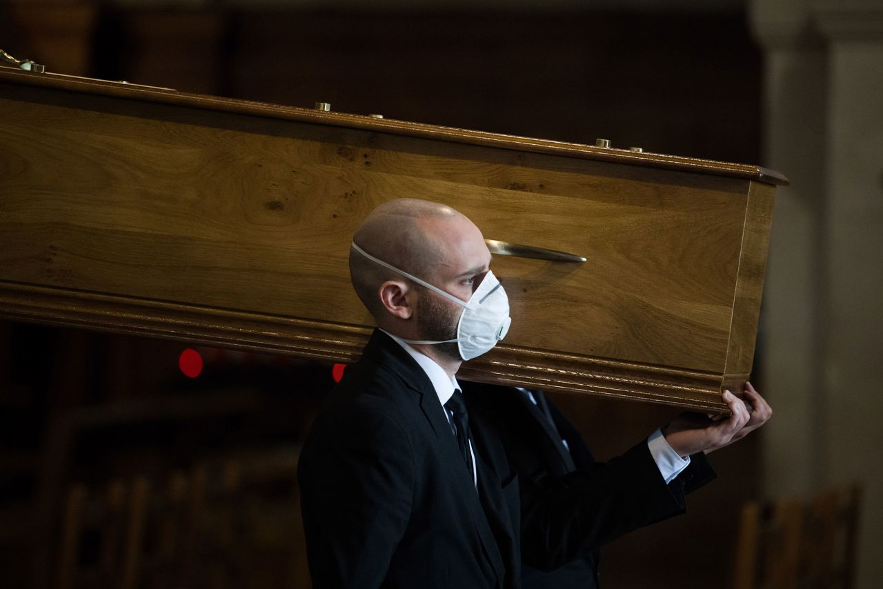 A pall bearer helps carry the coffin of a coronavirus victim through Saint Francois Xavier church at a funeral service in Paris, France, on April 16.