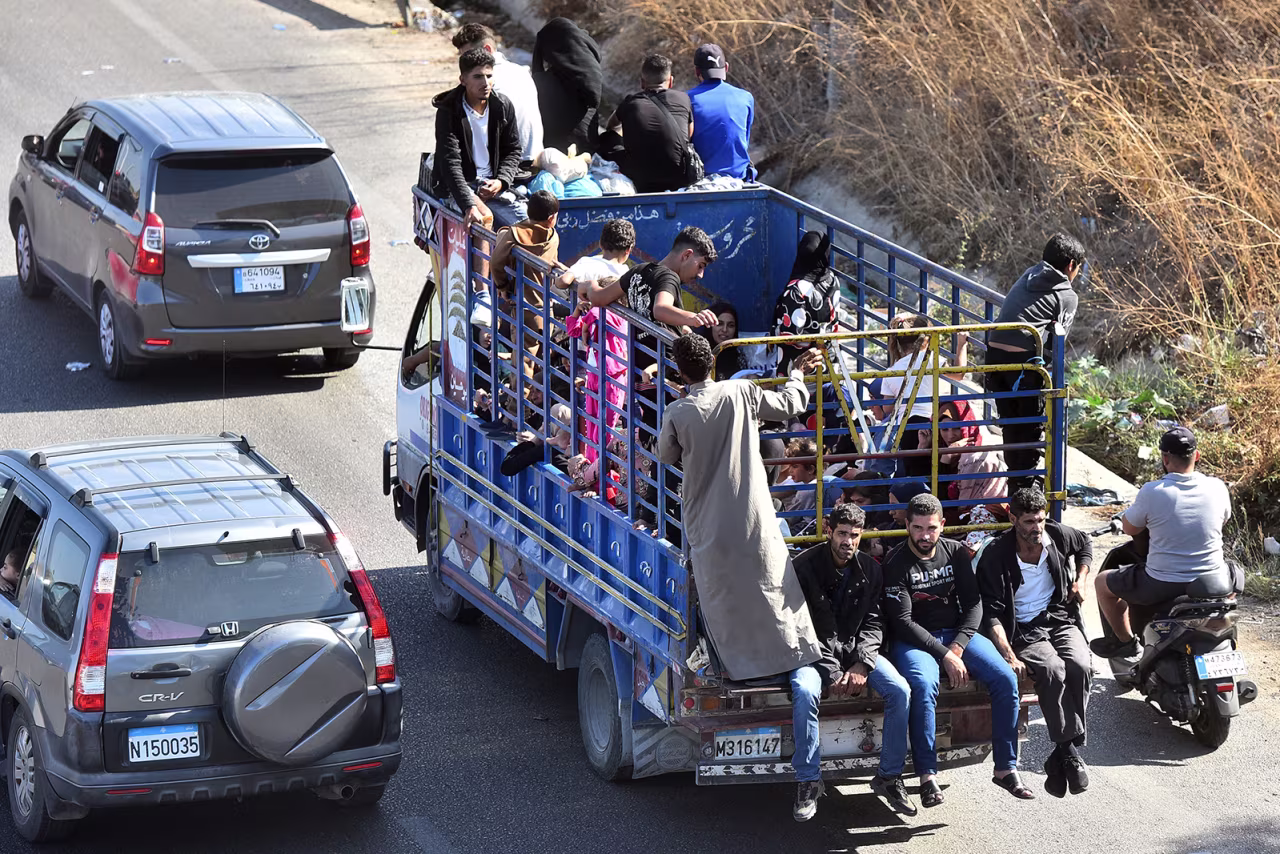 People sit with their belongings in the back of a truck as they arrive in the coastal town of Naameh, south of Lebanon's capital Beirut on September 24.