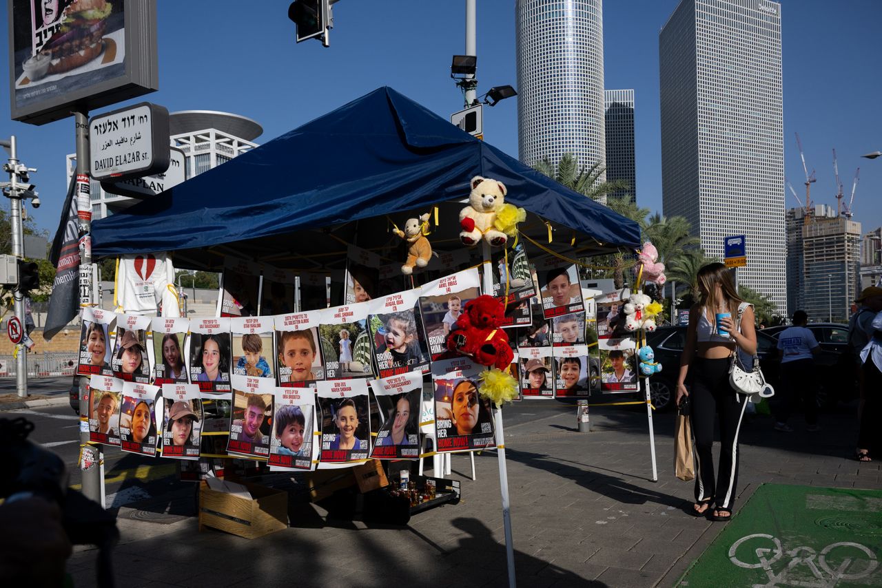 A person walks past a tent with faces of child hostages near Sarona on November 24, in Tel Aviv, Israel. 