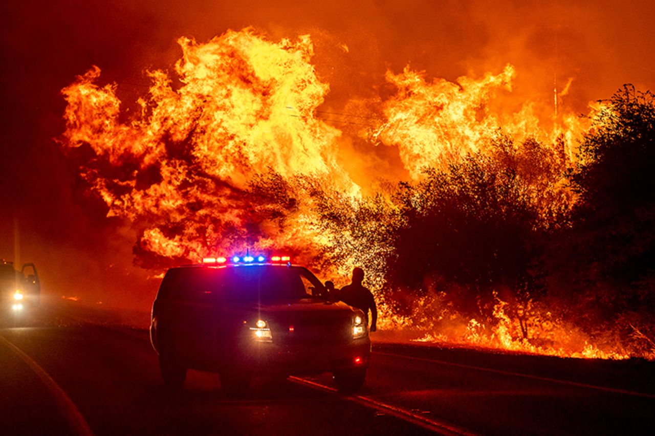 Flames lick above vehicles on Highway 162 as the Bear Fire burns in Oroville, California, on Wednesday, September 9. The blaze, part of the lightning-sparked North Complex, expanded at a critical rate of spread as winds buffeted the region. 