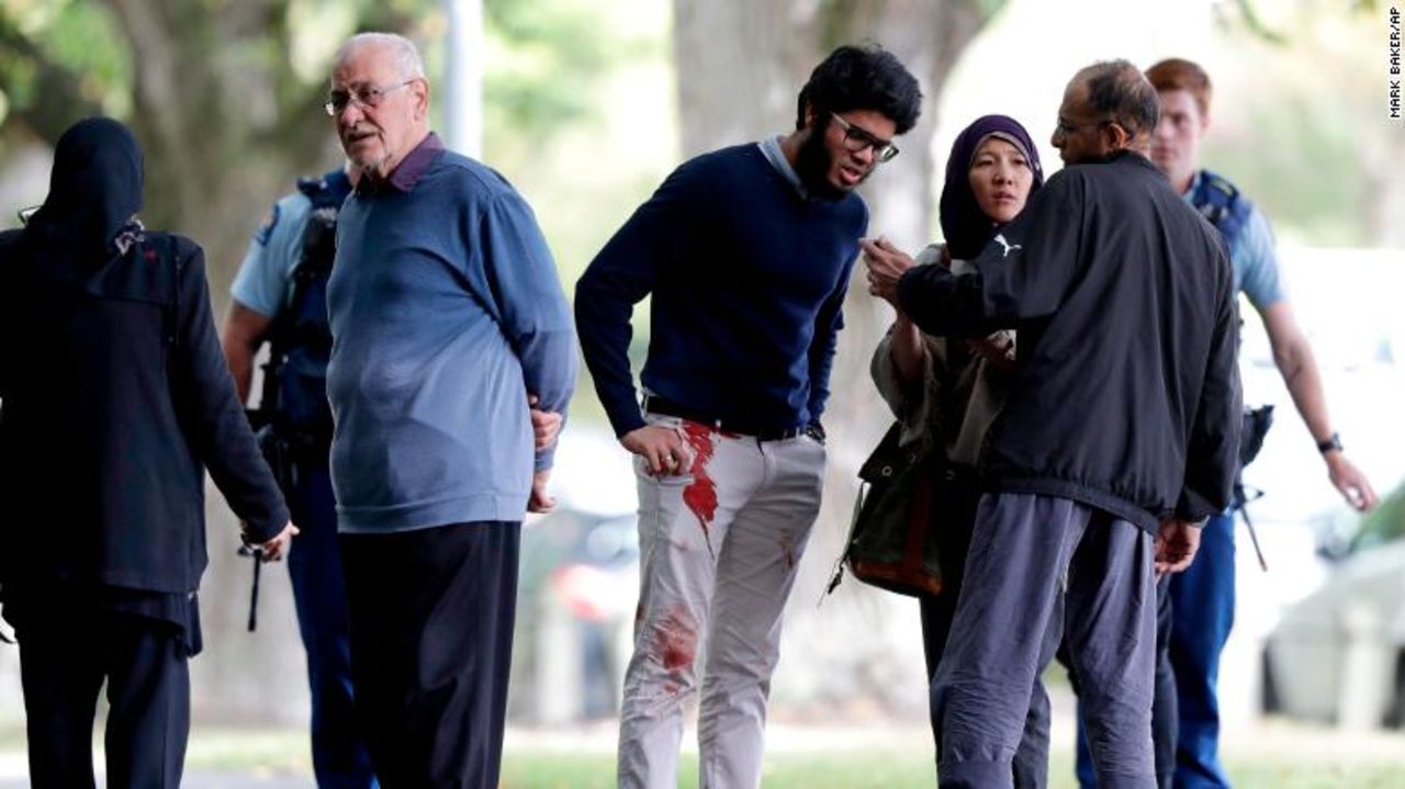 People stand across the road from one of the mosques attacked in central Christchurch on Friday.