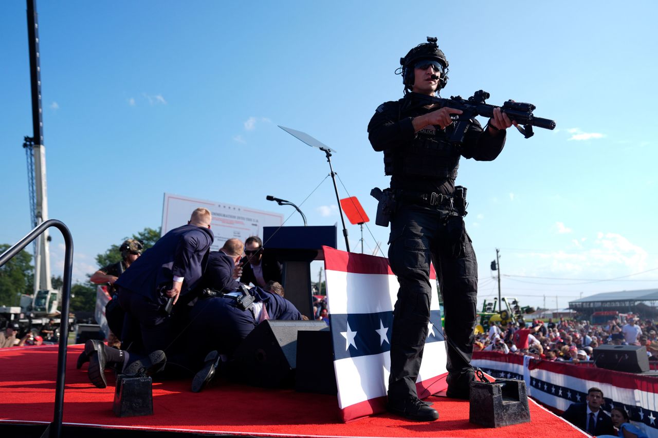 Trump is covered by Secret Service agents after loud bangs were heard at the rally. 