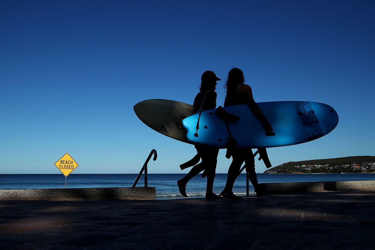 Surfers walk along Manly Beach in Sydney, Australia on April 5.