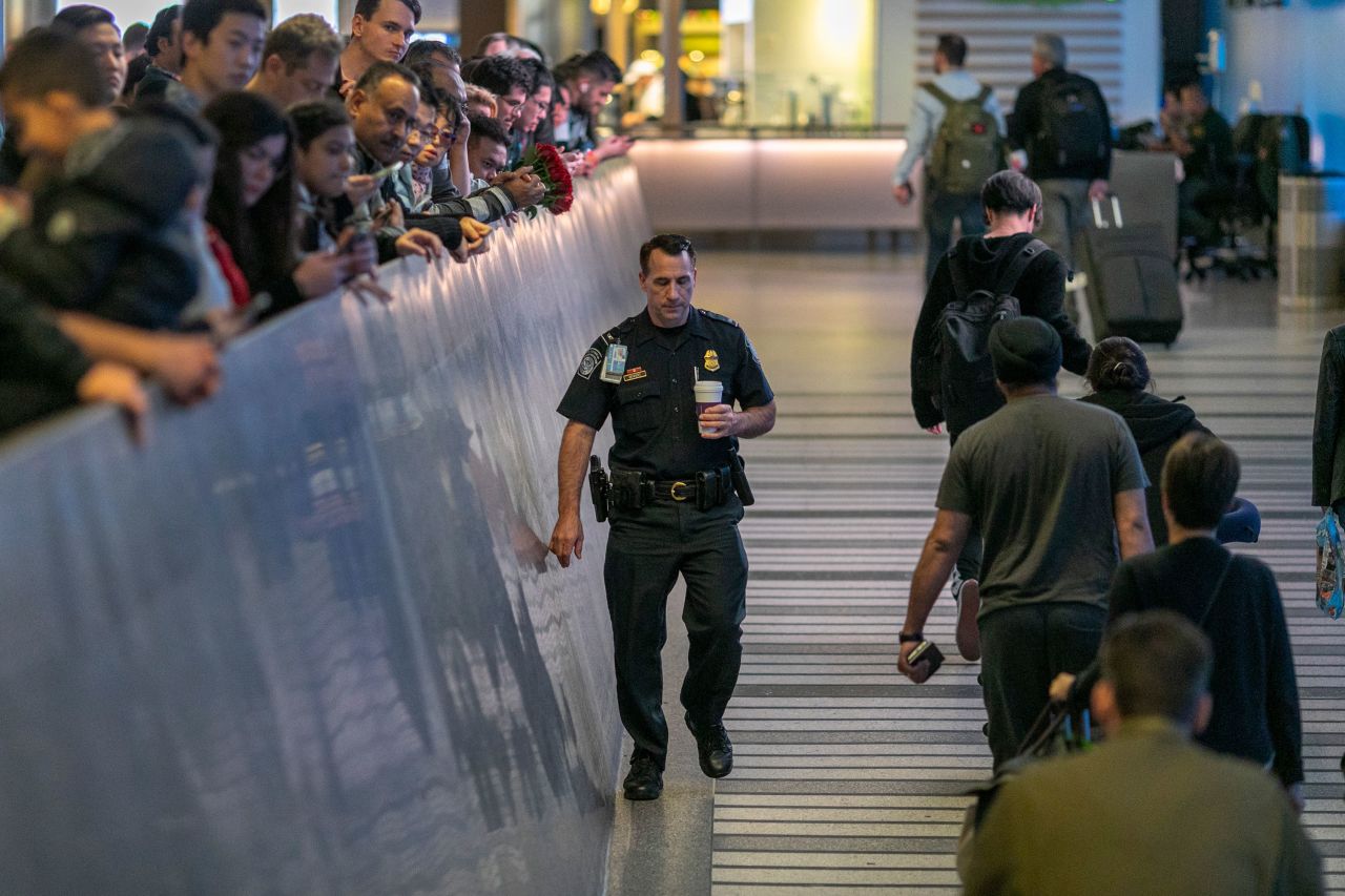 An airport officer walks past international travelers arriving to Los Angeles International Airport on the first day of health screenings for coronavirus of people coming from Wuhan, China on Tuesday, January 18 in Los Angeles, California. 