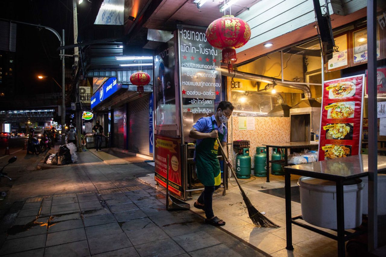 A restaurant workers sweeps up while closing his shop before the city-wide curfew on April 3, 2020 in Bangkok, Thailand.