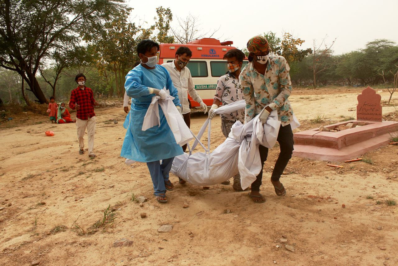 Family members along with graveyard workers perform the burial of a woman who died of Covid-19 in New Delhi, on March 30.