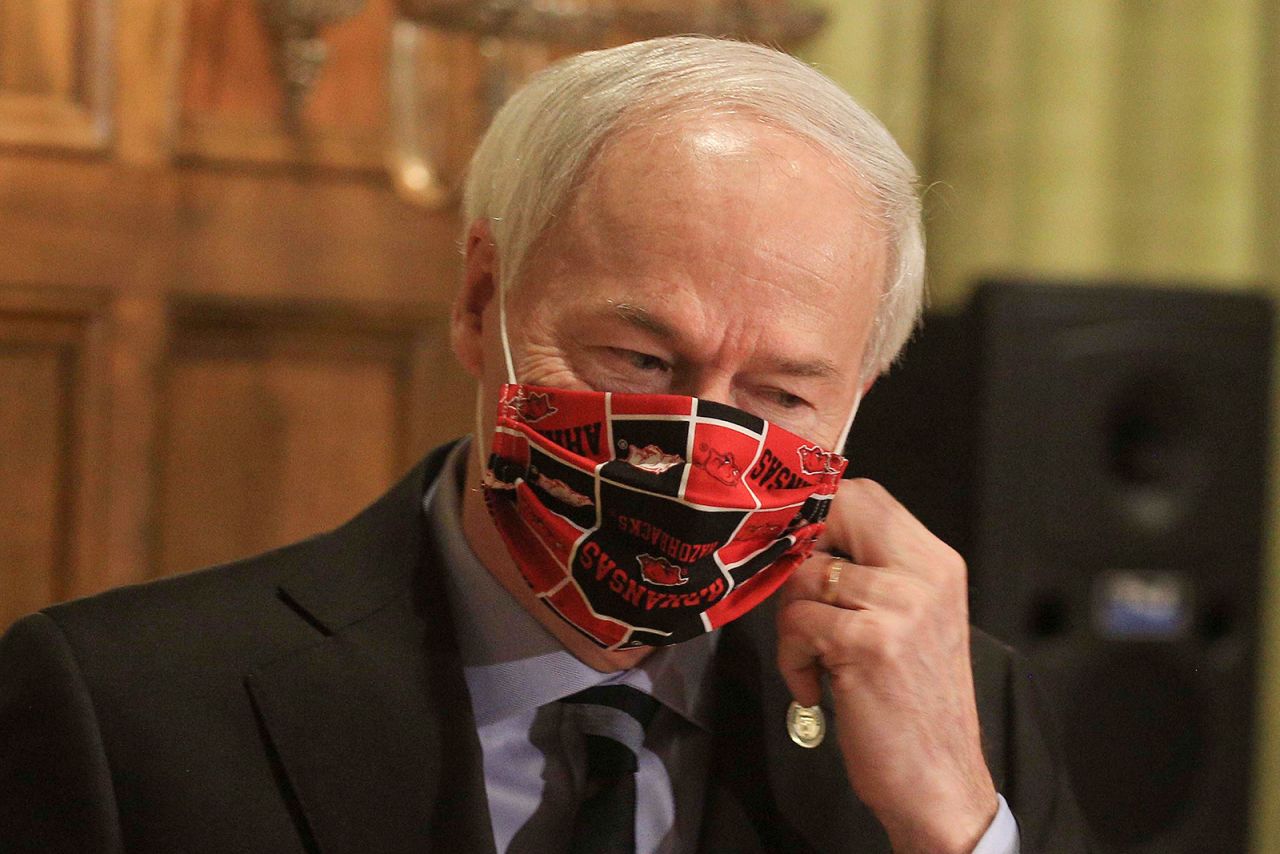 Gov. Asa Hutchinson takes off his Arkansas Razorbacks facemark as he arrives for the daily coronavirus briefing at the state Capitol in Little Rock on April 27.