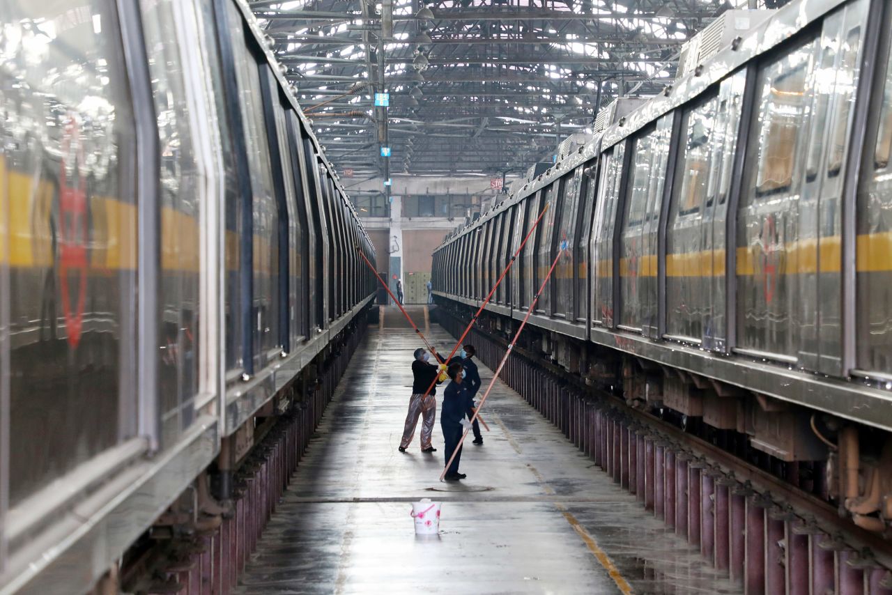 Workers disinfect the exterior a Delhi metro rail carriage. 