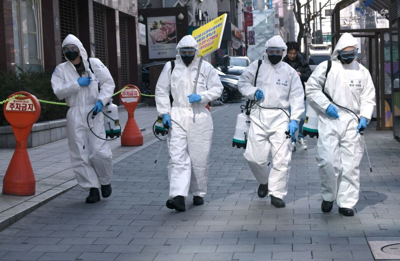 South Korean soldiers wearing protective gear spray disinfectant on the street to help prevent the spread of the coronavirus in Seoul today.